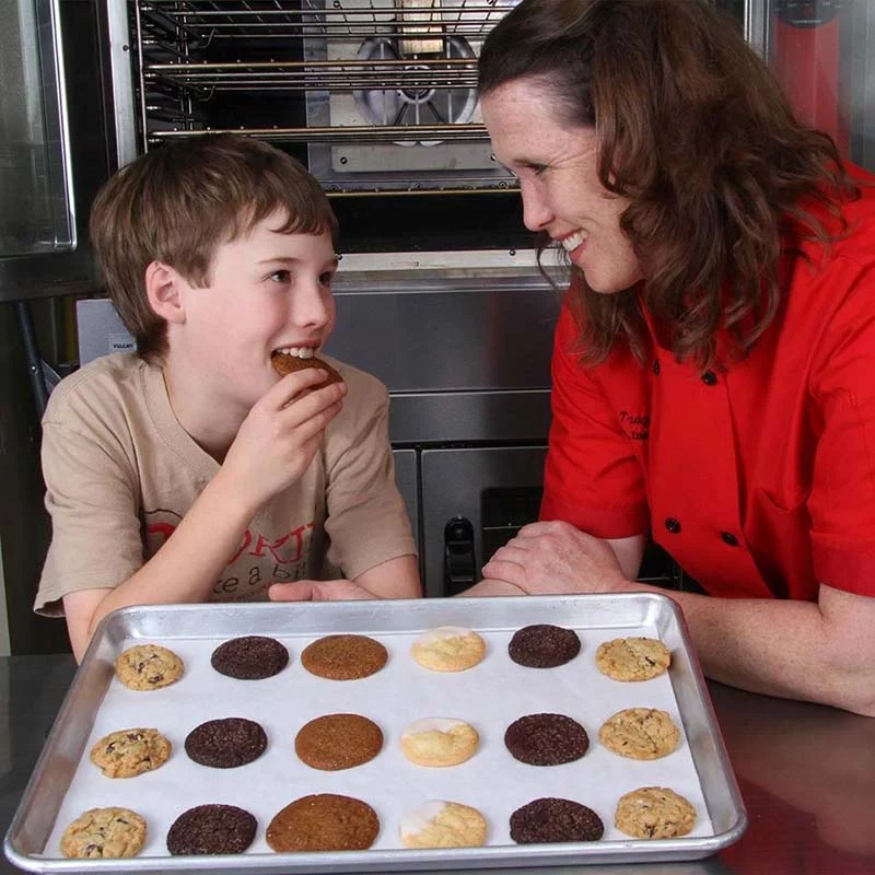 owner of cookie take a bite and her son enjoying a fresh baked cookie