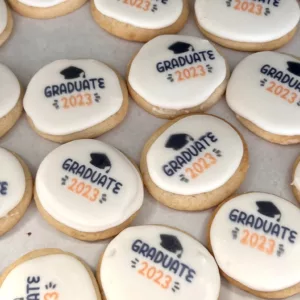 cookies in single layer with a grad hat and "GRADUATE 2023" stamped into the frosting