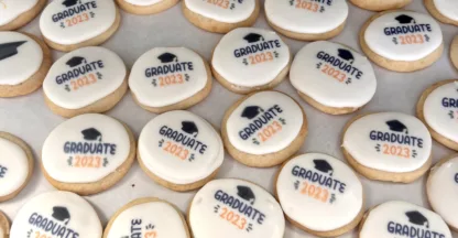 cookies in single layer with a grad hat and "GRADUATE 2023" stamped into the frosting