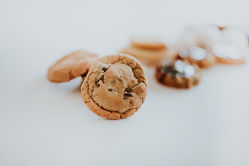 a close up of a perfect chocolate chip cookie with other cookies out of focus in the background