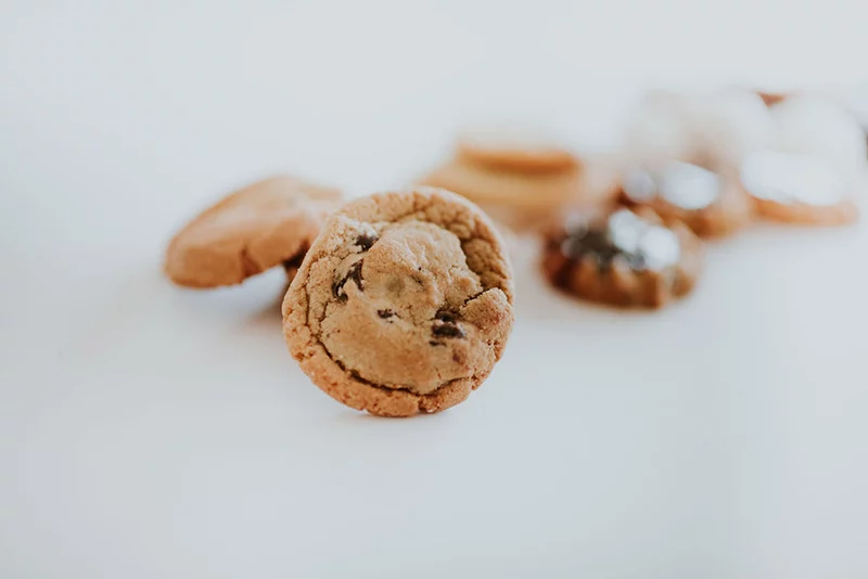 a close up of a perfect chocolate chip cookie with other cookies out of focus in the background