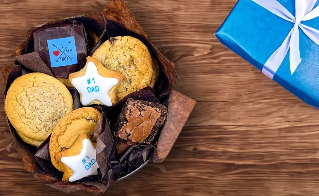 Open, overhead of Father's Day Cookie Tin on wooden table with gift in blue wrapping paper.