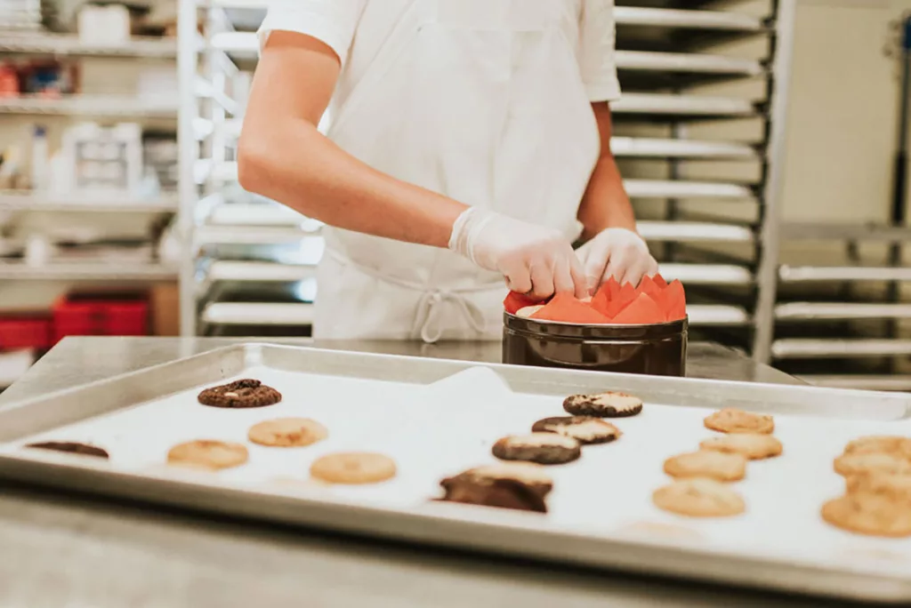 A row of locally made cookies on a baking sheet in the kitchen of a bakery.