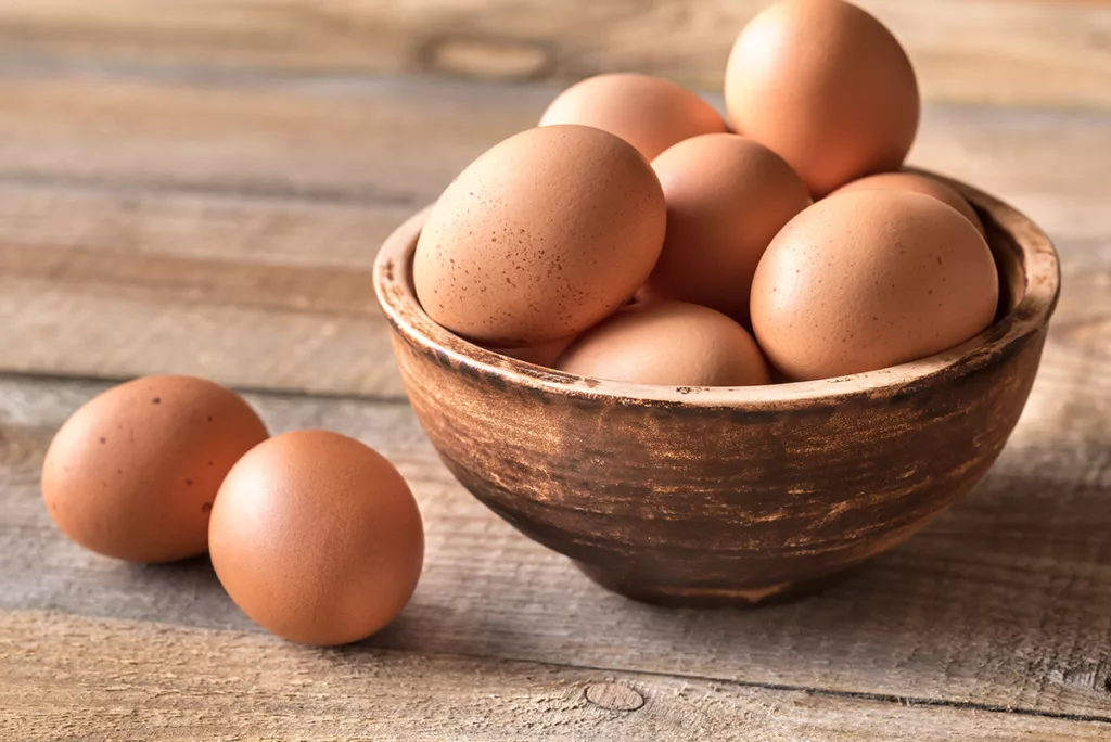 A bowl of raw eggs on a  wooden table